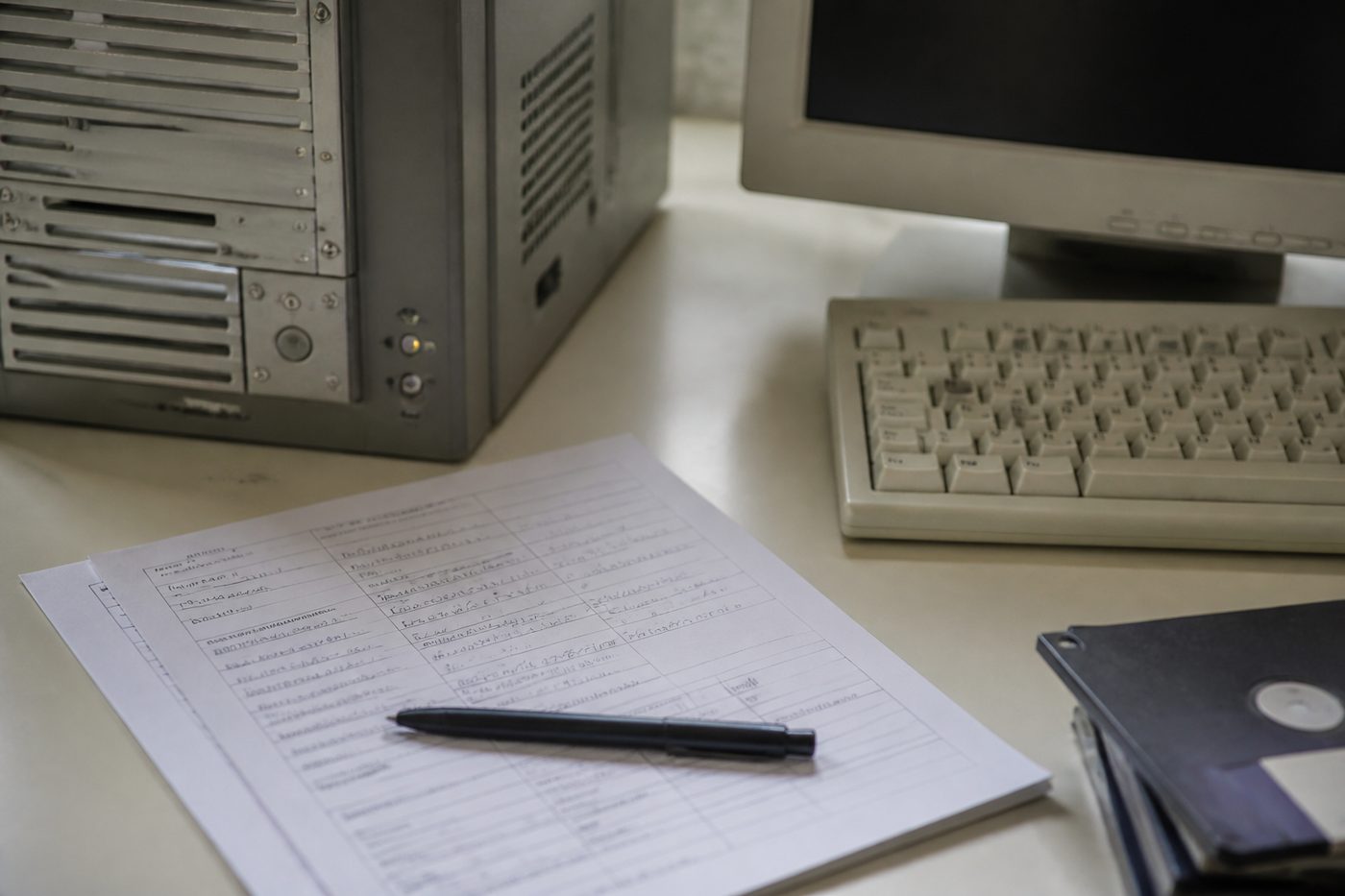 Formulaire papier rempli au stylo posé à côté d'un clavier d'ordinateur, sur un bureau en bois clair.
